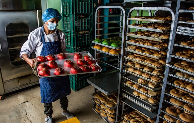 Fornaio latino che prepara l'impasto e cuoce pan brioche e biscotti colorati