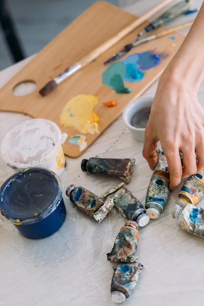 Forniture di pittura Classe d'arte Hobby creativo Artista femminile professionista che sceglie tubo acrilico o pittura a olio sul posto di lavoro con strumenti per tavolozza e pennello