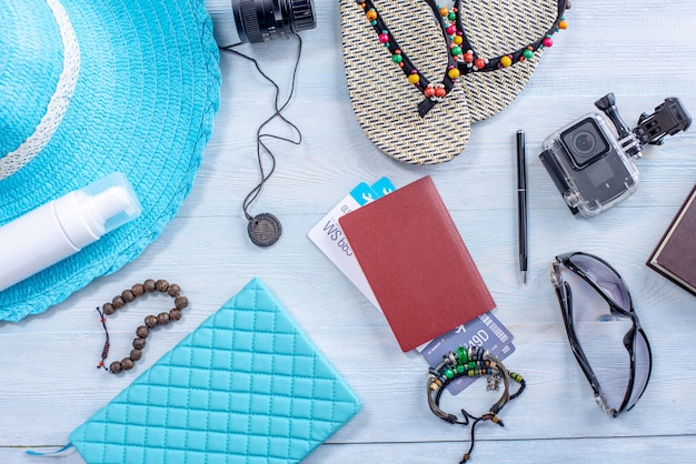 Forniture per le vacanze di viaggio: cappello, occhiali da sole, infradito, fotocamera, passaporto su sfondo blu