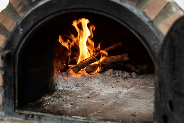 Forno a legna artigianale costruito all'esterno con la porta aperta e fuoco all'interno