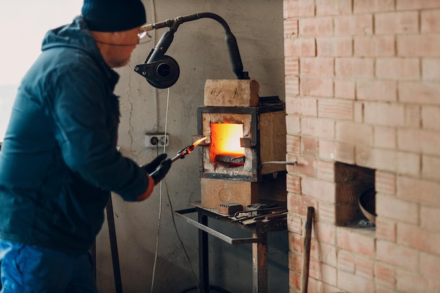 Forno della fucina del fabbro con fiamma calda Smith mise dentro e riscaldava un pezzo di ferro d'acciaio nel fuoco del forno della fucina rovente