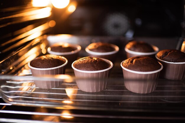 Forno di casa aperto con gustosi muffin al cioccolato in forme da forno su teglia