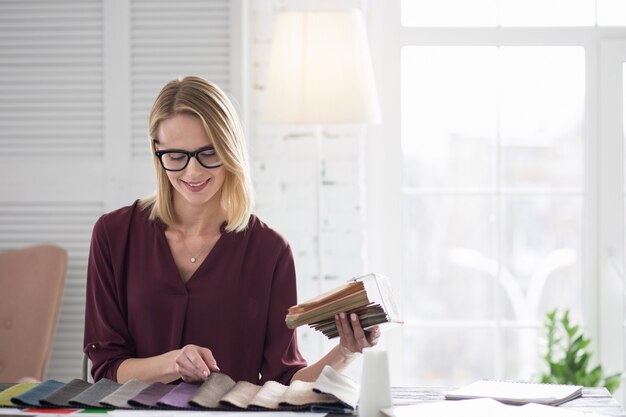 Forse questo. Designer femminile riflettente che propone al tavolo e scegliendo la tappezzeria