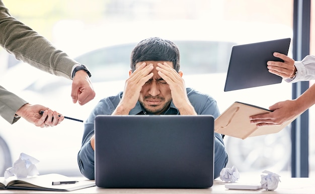 Forse se li ignoro se ne andranno Inquadratura di un bel giovane uomo d'affari seduto in ufficio che si sente stressato mentre i suoi colleghi gli fanno pressione