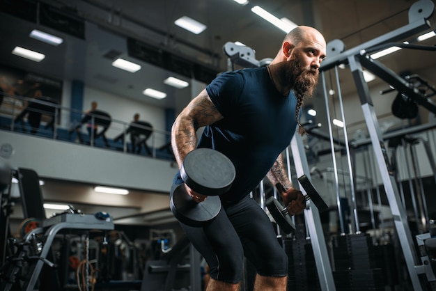 Forte atleta con manubri, allenamento in palestra