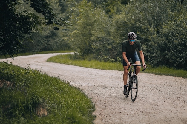 Forte atleta maschio in bicicletta sul sentiero nel bosco