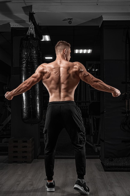 Forte uomo atletico modello di fitness in posa muscoli della schiena tricipite latissimus su sfondo scuro
