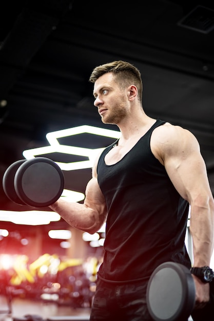 Forte uomo bello che lavora sodo in palestra. Culturista che allena i suoi bicipiti.