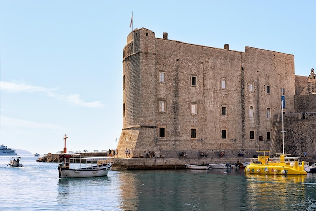 Fortezza di Dubrovnik e barche con persone nel porto del mare Adriatico, Croazia