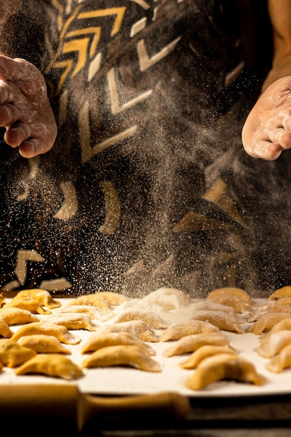 Forti mani da uomo cospargono gnocchi di farina piatto nazionale ucraino