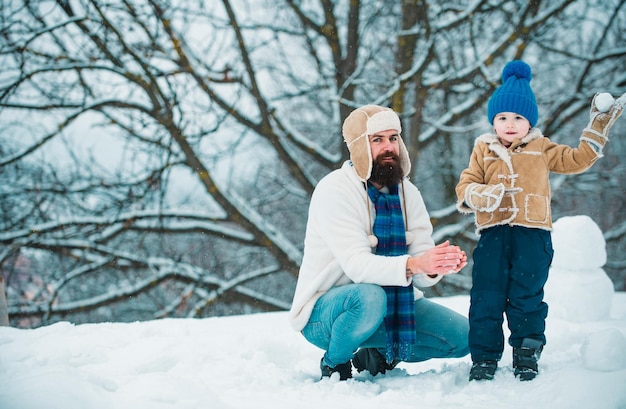 Fortunato padre e figlio giocano in inverno a Natale il giorno dei padri felice bambino che gioca con la palla di neve