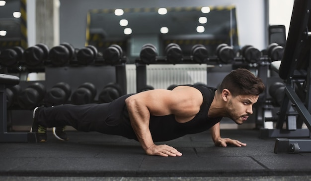 Forza e motivazione. Uomo ispanico che fa flessioni in palestra, copia spazio