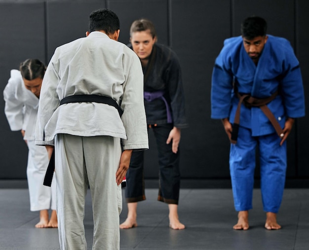 Forza fitness e rispetto tra l'istruttore di karate che guida una classe inchinarsi e salutare uno studente di arti marziali in un dojo o in uno studio Allenamento di gruppo eterogeneo e apprendimento delle abilità di autodifesa e resistenza