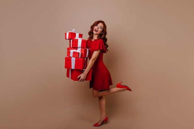 Foto a figura intera di una ragazza di compleanno estatica che tiene scatole regalo Donna caucasica sognante che si gode la festa di Capodanno con regali