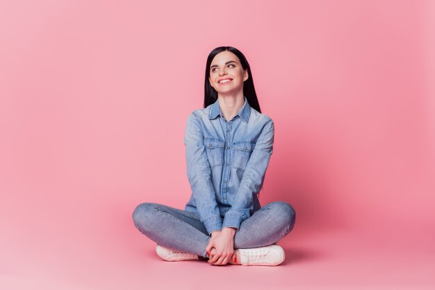 Foto a grandezza naturale del contenuto ragazza candida sedersi sul pavimento godetevi il fine settimana indossando abiti di bell'aspetto isolati su uno sfondo di colore rosa