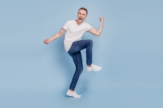 Foto a grandezza naturale del giovane uomo allegro felice sorriso positivo celebrare la vittoria campione pugni mani isolate su sfondo di colore blu