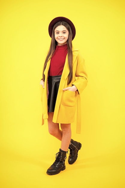 Foto a lunghezza intera di ragazza teen bruna indossare abiti casual autunno cappotto isolato su sfondo giallo Ritratto di adolescente felice Ragazza sorridente