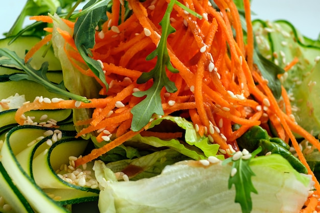Foto a macroistruzione di insalata con il cetriolo, la carota piccante, la rucola e il sesamo