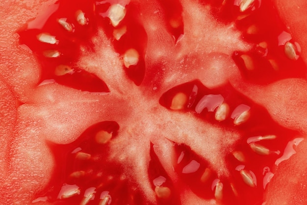 Foto a macroistruzione di una fetta di pomodoro tagliata a metà con semi. Consistenza della fetta di pomodoro