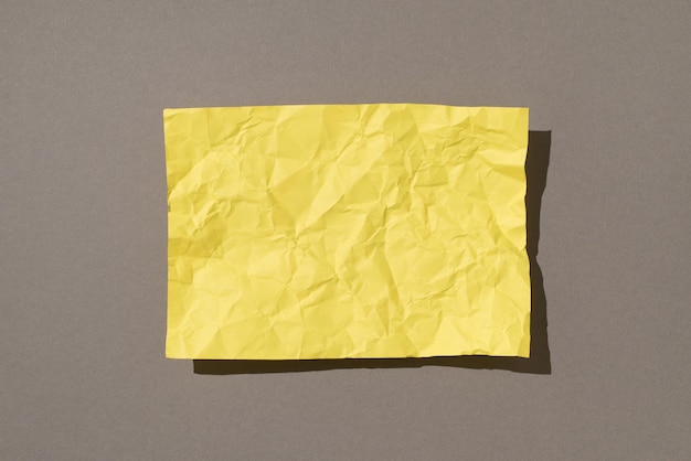 Foto aerea di carta gialla sbriciolata al centro isolata sullo sfondo grigio