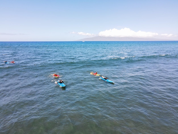 Foto aerea di surfisti seduti su tavole da surf e in attesa di onde in mezzo all'oceano