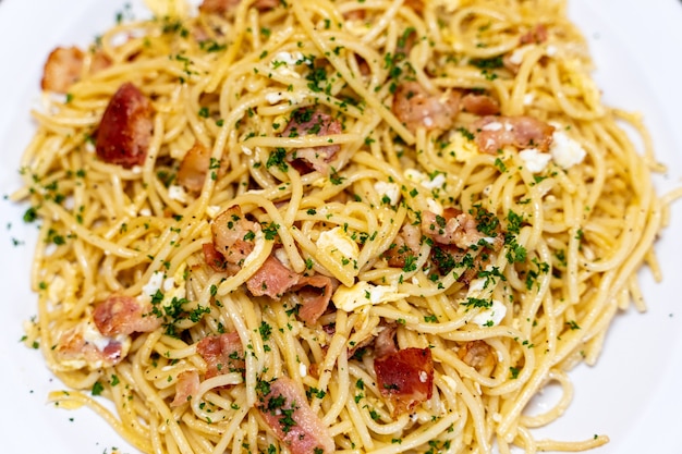 Foto aerea di un piatto di spaghetti alla carbonara servito su un piatto bianco