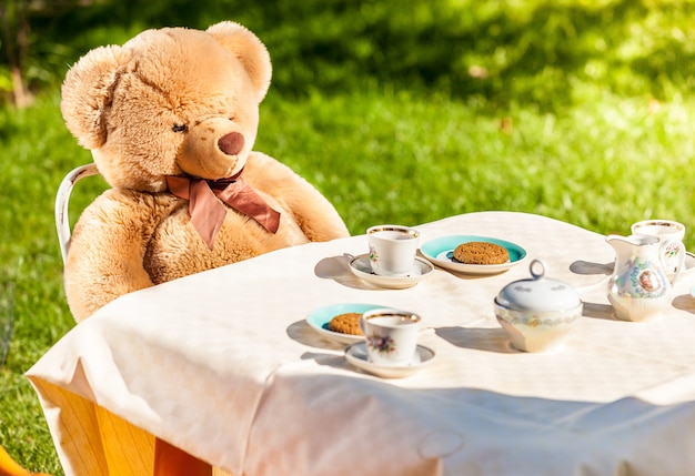 Foto all'aperto di un orsacchiotto seduto in giardino e che fa colazione all'inglese