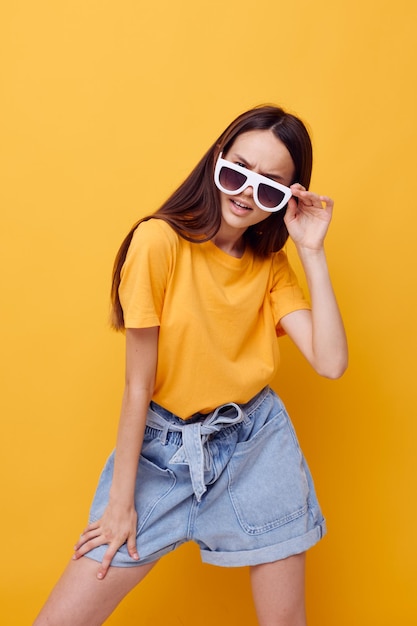 Foto bella ragazza con i capelli lunghi che indossa occhiali da sole in posa sfondo isolato