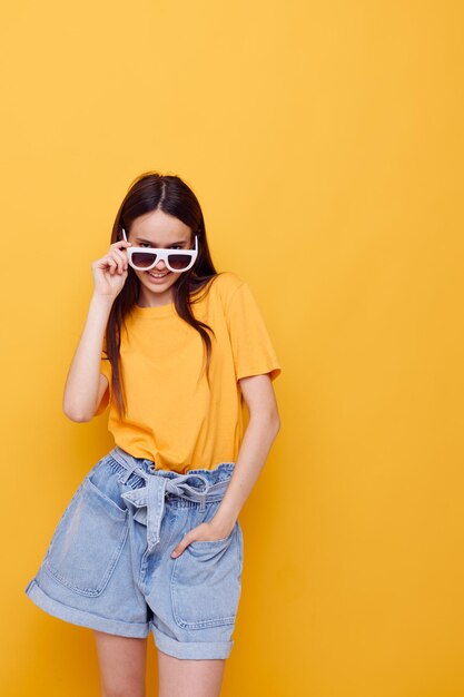 Foto bella ragazza con i capelli lunghi che indossa occhiali da sole in posa sfondo isolato