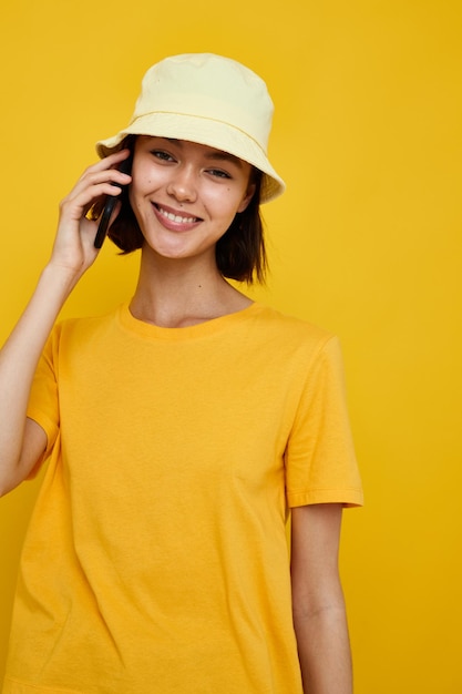 Foto bella ragazza gialla maglietta e cappello in stile estivo con stile di vita del telefono inalterato