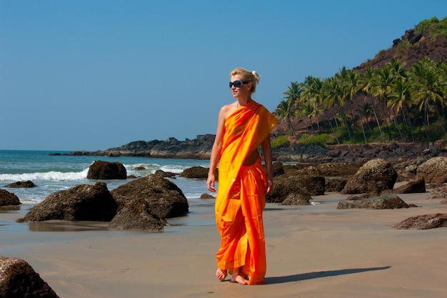 Foto bella ragazza in piedi sulla spiaggia di Goa vicino alle palme