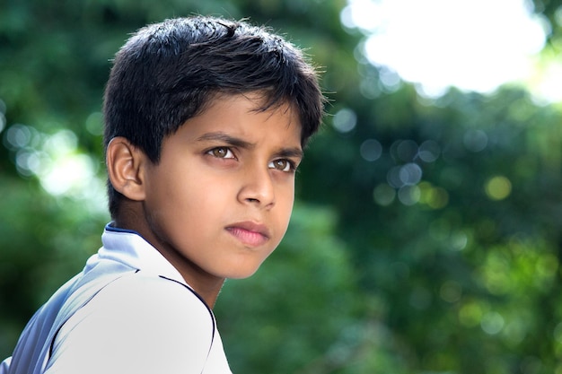 Foto candida di un giovane ragazzo indiano ritratto da vicino che guarda a distanza in sguardo serio