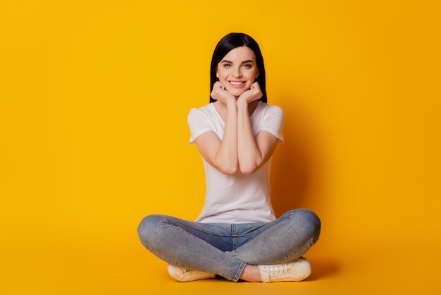 Foto completa del corpo di una giovane ragazza seduta sul pavimento che riposa da sogno isolato sfondo di colore giallo vivido brillante