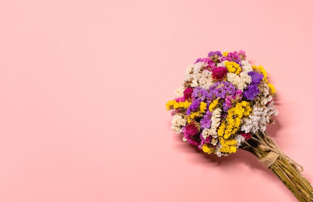 foto con bouquet multicolore con fiori secchi limonium su sfondo rosa pastello