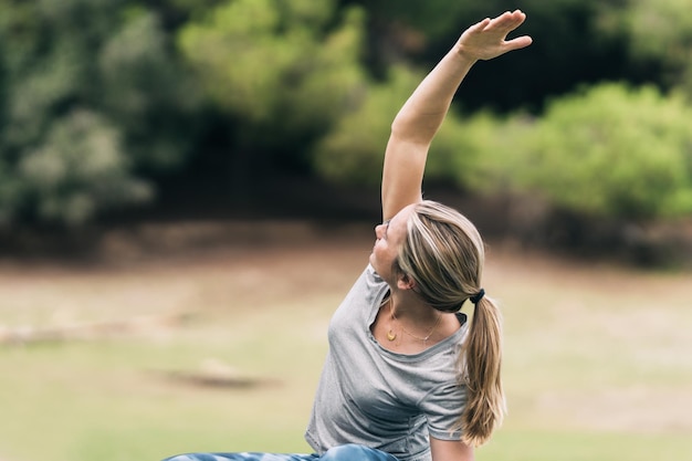 Foto con copia spazio di una donna che allunga la schiena seduta sul pavimento in un parco