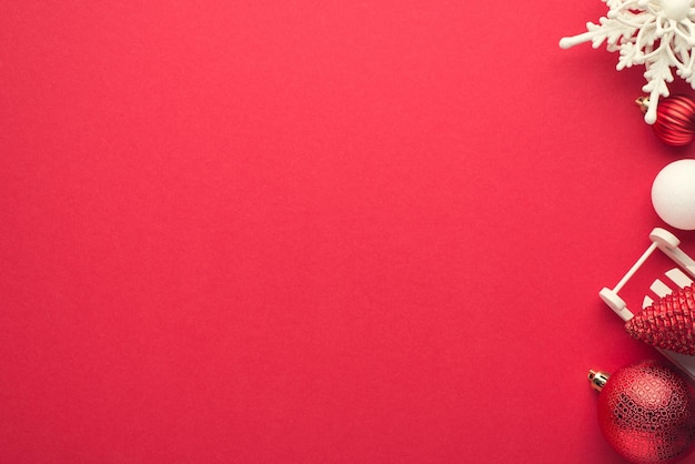 Foto dall'alto di decorazioni per alberi di Natale bianche e rosse con fiocchi di neve e piccola slitta su sfondo rosso isolato con copyspace