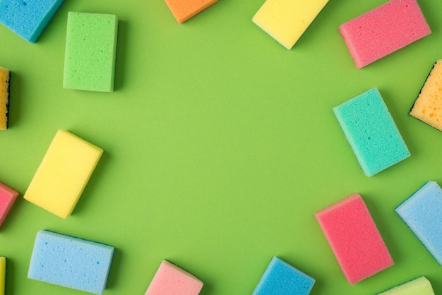 Foto dall'alto di spugne abrasive multicolori su sfondo verde isolato con copyspace al centro