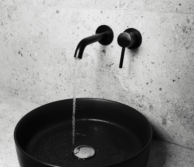 Foto dei dettagli del bagno lavandino e rubinetto neri con acqua corrente
