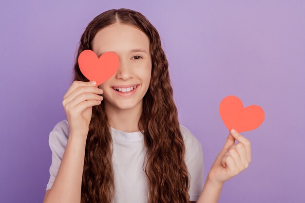 Foto del cuore di san valentino della carta dell'occhio della copertura della giovane ragazza isolato sopra fondo porpora