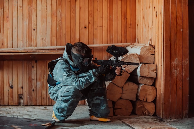 Foto del giocatore di paintball in maschera di protezione e camuffamento che punta con la pistola paintball Fuoco selettivo