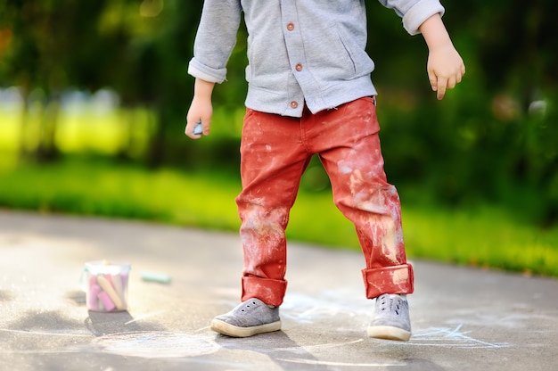 Foto del primo piano del disegno del ragazzino con gesso colorato su asfalto.