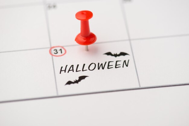 Foto del primo piano del segno sul calendario alla trentunesima iscrizione halloween e disegno di pipistrelli con puntina rossa