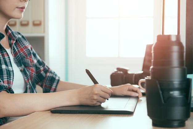 foto del primo piano della bella ragazza di lavoratore di ufficio bella utilizzando il pad digitale disegno di editing fotografico per la società per azioni di foto di affari che vende in studio moderno.