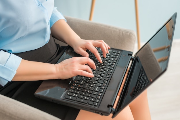 Foto del primo piano delle mani femminili con un computer portatile