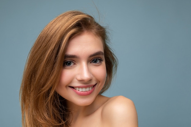 Foto del primo piano di giovane bella donna bionda sorridente con le emozioni sincere isolate su fondo