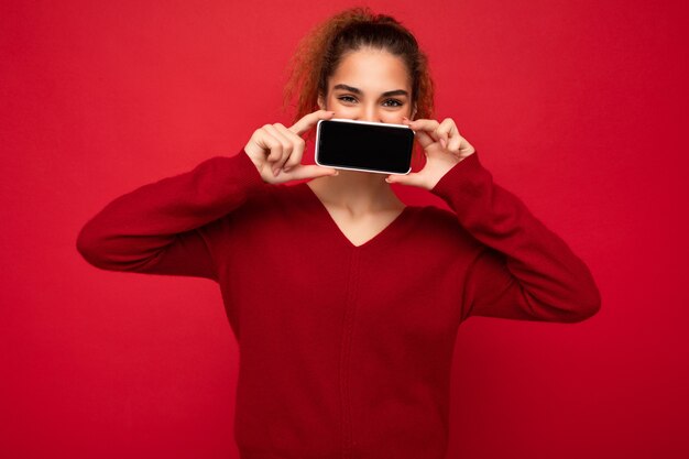 Foto del primo piano di giovane persona di sesso femminile divertente felice che porta maglione rosso scuro isolato sopra rosso