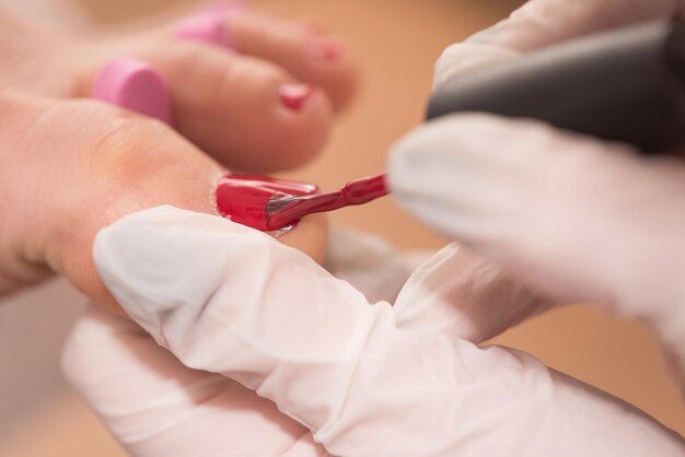 Foto del primo piano di piedi femminili al salone spa sulla procedura di pedicure e manicure