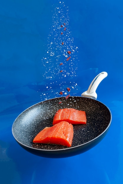 Foto del primo piano di salmone crudo fresco, filetto di trota in padella sullo sfondo blu dell'acqua