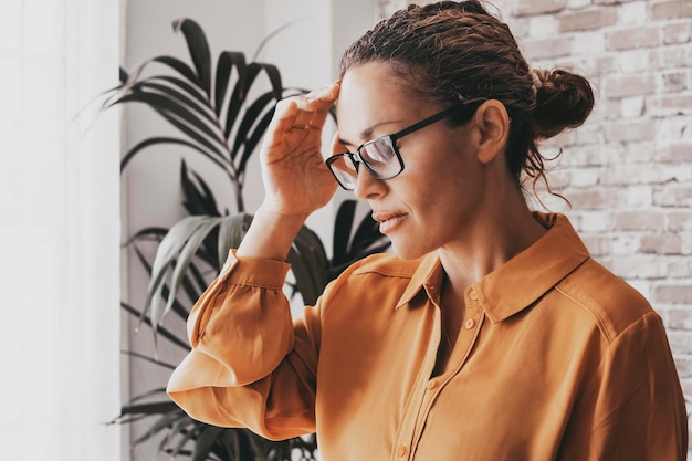 Foto del primo piano di una giovane donna seduta su un divano con gli occhi chiusi che si tocca la testa mentre soffre di emicrania Persone dello stile di vita sullo sfondo dell'ufficio affari