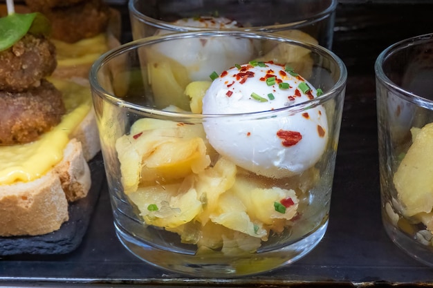 Foto del primo piano di una tipica tapa o aperitivo servito in un bar spagnolo patate e un uovo fritto presentato in un antipasto di vetro noto come uova rotte